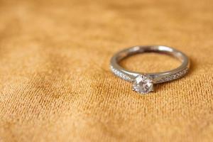 anillo de diamantes de joyería sobre fondo de tela dorada de cerca foto