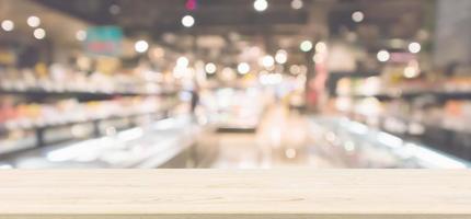 Wood table top with Abstract supermarket grocery store refrigerator blurred defocused background with bokeh light photo
