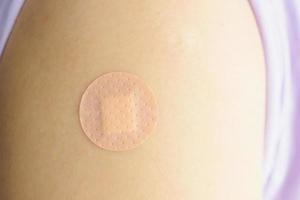 Close up circle brown adhesive bandage on patient arm after medicine injection or vaccination photo