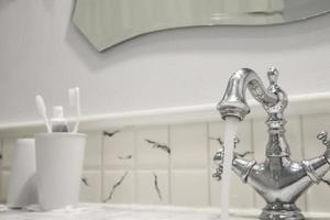 agua del grifo en el baño con cepillo de dientes foto