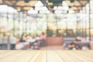 Empty wooden table top with cafe restaurant coffee shop interior abstract blur defocused with bokeh light background for montage product display photo