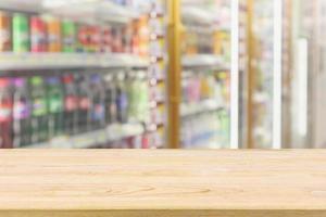 Wood table top with Beverage soft drink bottles in convenience store refrigerator shelves blurred background photo