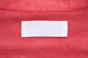 etiqueta de ropa blanca en blanco sobre fondo de textura de tela de camisa de lino rojo foto