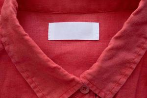 White blank clothing tag label on red linen shirt fabric texture background photo