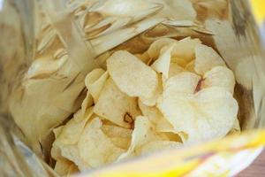 Potato chips in open snack bag close up photo
