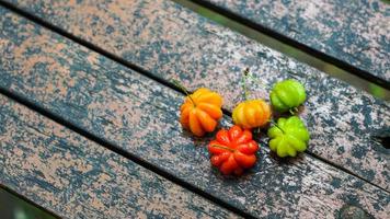 The combination of colored Brazilian cherry fruits with defocus and blurred background on an old wood table photo