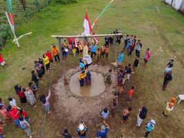 Blitar, Indonesia - September 11th 2022 Aerial view of housewife who is taking part in a banana tree climbing competition to get a prize and is seen by many people photo