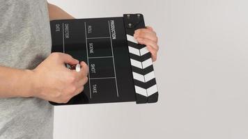 The hand is holding a black clapper board and marker Pen on white background. photo