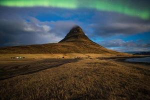 aurora o la luz del norte sobre la montaña kirkjufell la icónica montaña famosa en forma de triángulo en la región oeste de islandia. foto