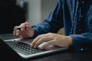 Man using computer laptop working internet searching social media and communications digital technology online at desk. photo