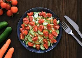 Vegetables salad with cucumber, carrot, tomato and cabbage on a plate. photo