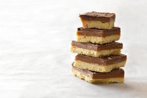 Millionaires shortbread with chocolate and caramel on parchment paper. photo