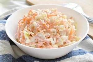 Coleslaw salad with carrot and cabbage on a white bowl. photo