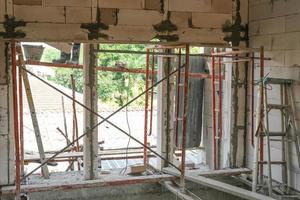 metal scaffolding install use for high level.  concrete wall plaster cement on wall for building new house. photo