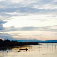 silueta de un hombre pescando por la tarde. puesta de sol en el lago limboto, indonesia foto