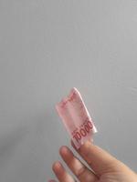 Isolated photo of a hand holding a hundred thousand rupiah banknote.