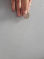 foto aislada de una mano sosteniendo una moneda de mil rupias.