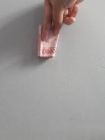foto aislada de una mano que sostiene un billete de cien mil rupias.