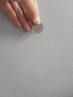 Isolated photo of a hand holding a thousand rupiah coin.