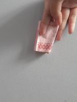 Isolated photo of a hand holding a hundred thousand rupiah banknote.