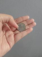 foto aislada de una mano sosteniendo una moneda de mil rupias.