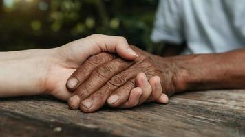 Hands of the old man and a woman hand on the wood table photo