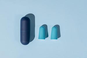 Blue ear plugs made of foam for comfortable sleep on blue background. Insomnia concept, flat lay photo