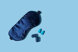 Quality sleep concept blue sleep mask and earplugs on blue background. Accessories for good rest at night, block of any light and sound. photo