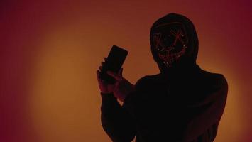 Digital security Concept. Anonymous hacker with mask holding smartphone hacked. photo