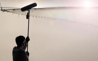 Sound boom operator recording sound by microphone fisher for movie set in a studio. photo