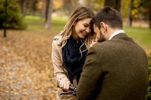 Young couple in the autumn park with electrical bicycle photo