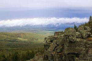 paisaje escénico con montañas y valle forestal y cielo nublado en el fondo. montes urales, rusia. foto