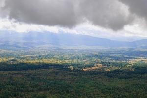 View on a forest valley in mountains in storm cloudy weather with sunlight. Ural Mountains, Russia. photo