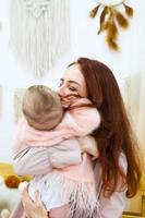 Young mother is holding her little daughter in hands. Candid family portrait. photo