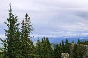 View on mountains landscape with fir trees on foreground and cloudy sky on background. Ural Mountains, Russia. photo