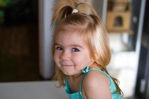 Candid lifestyle portrait of lovely blond little girl in sunlight in the morning. photo