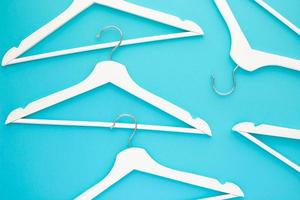 White wooden hangers on blue background photo