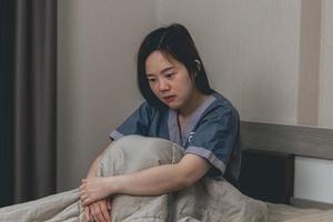 stressed chinese female architect having headache while working on blueprint in office. young asian girl designer sitting at desk using computer head painful. photo