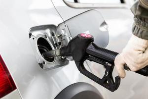 mano en guante de tela de algodón blanco repostando un coche metálico gris en una gasolinera - cierre con enfoque selectivo foto