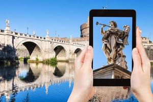 tourist photographs Angel statue on bridge in Rome photo
