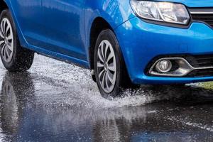 coche azul cruzando un charco con agua salpicada a la luz del día cerrada foto