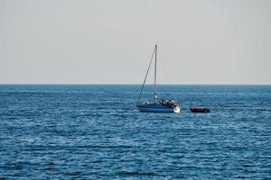 Sailing boat floating on blue quiet sea in summer, calm weather, clear sky background, adventure photo