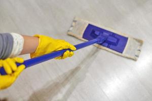 Girl in protective gloves cleaning floor using flat wet mop. photo