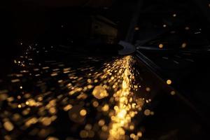 Sparks of yellow color. Metal treatment. Lights in dark. Sparks from split grinding disc. photo