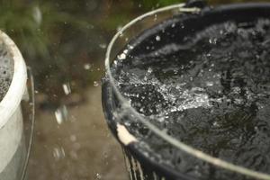 Rain is dripping into bucket. Water splashes in bucket. photo