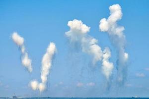 nubes blancas de fibra de carbono en el cielo azul que esconden destructores navales de misiles antibuque, espectáculo militar foto