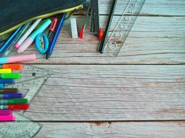 The top view of  stationery in school bags and pencils arranged on a wood teble background. photo