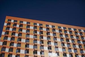 Orange building in modern style. House with identical windows. Lot of apartment building in city. New housing. photo