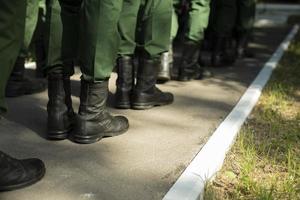 Military stands in row. Soldiers' shoes. Boots and military uniforms. photo