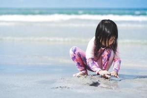 Portrait image child playing sand on sandy beach. Learning through play. Education with nature concept. Kid wearing swim suit at sea. Summer time. Sensory and playing. Empty space. photo